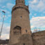 Ein runder Turm lehnt an einer Stadtmauer