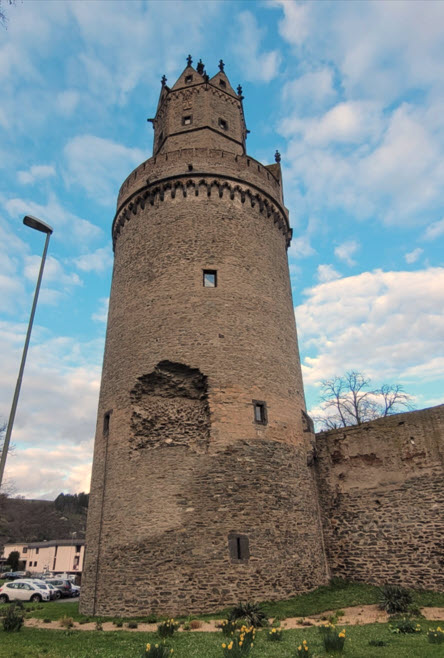 Ein runder Turm lehnt an einer Stadtmauer