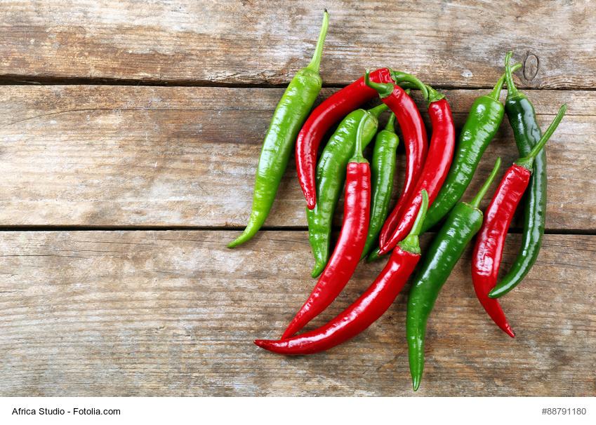 Rote und grüne Chilisamen liegen auf einem Holzschneidebrett