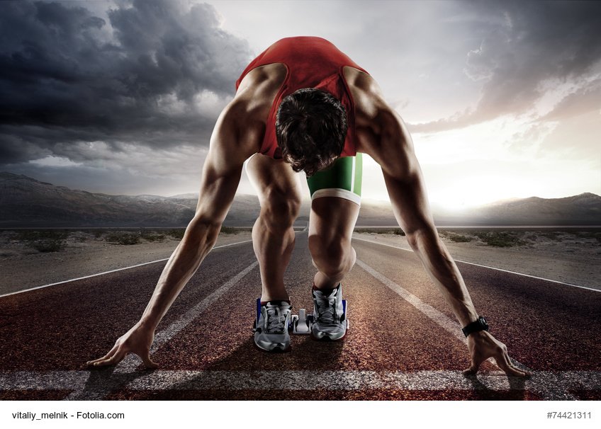Ein männlicher Leichtathlet befindet sich auf der Aschenbahn in Startposition